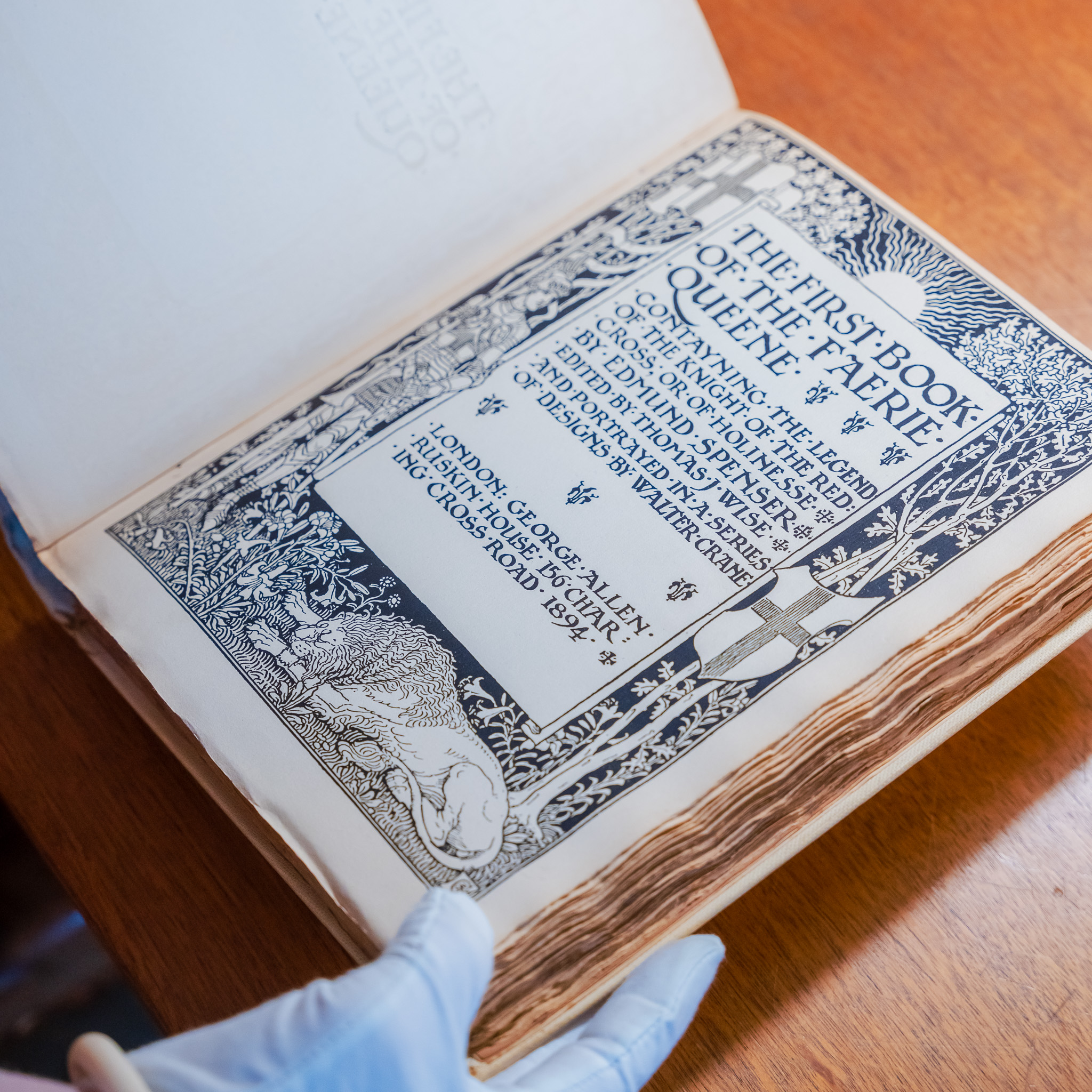 Bibliotekar gennemgår arkivmateriale med hvide handsker.