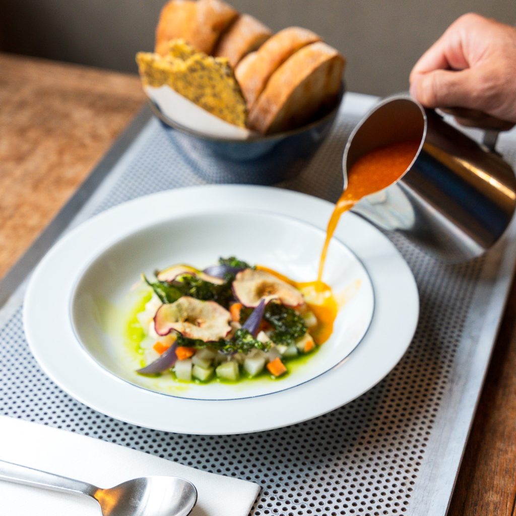 Suppe med hummerbisque på rismælk med kartoffel, gulerod, selleri, syltede rødløg, tørret kål, tørrede æbleskiver og estragonolie.